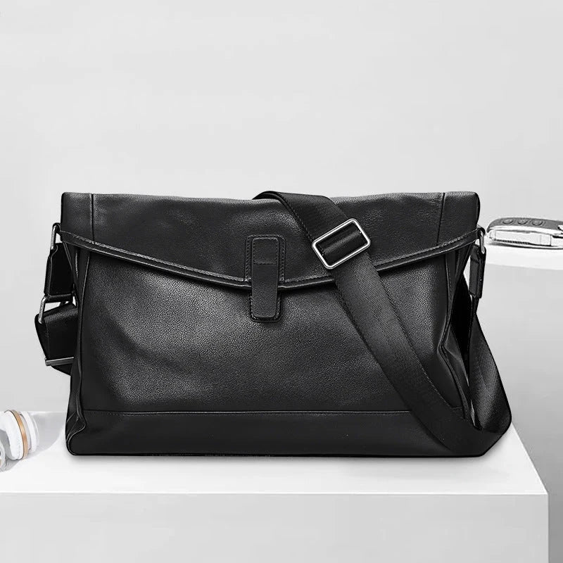 Porte-documents cuir noir homme avec bandoulière ajustable sur table blanche