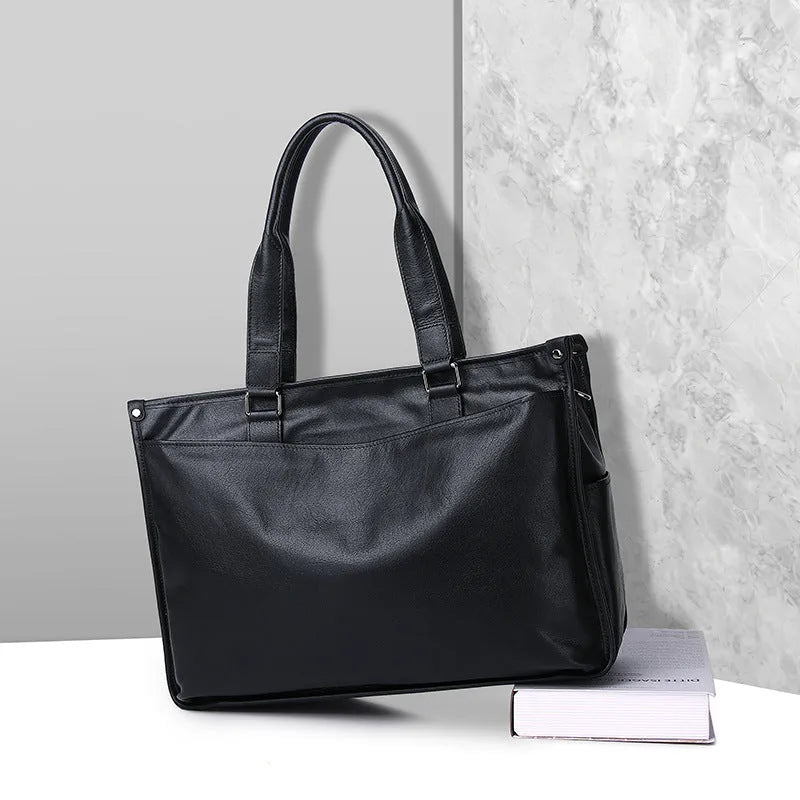 Mallette en cuir noir posée sur un livre devant un mur gris