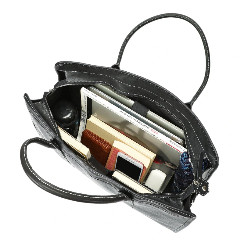 Sac à main en cuir noir posé sur une surface en bois avec fond gris