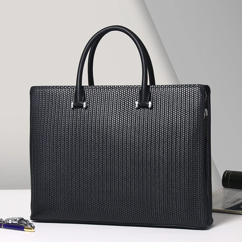 Porte-documents en cuir noir texturé posé sur bureau blanc