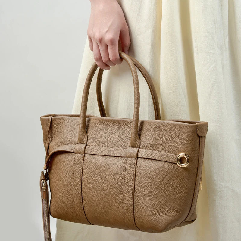 Cabas en cuir marron porté à la main sur une robe claire